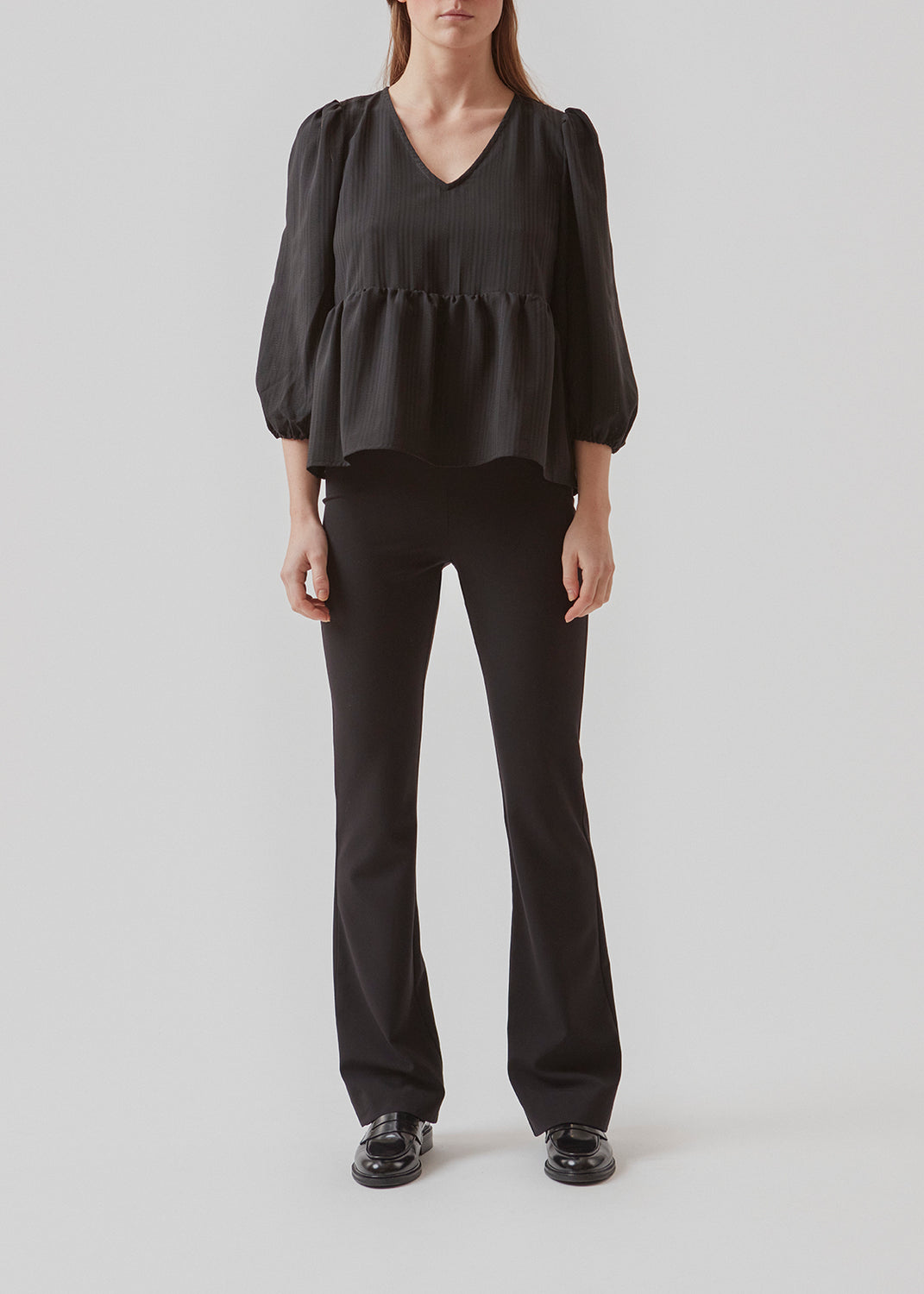 Top i sort i løs silhuet med 3/4 lange pufærmer, v-udskæring i halsen og en skæring i taljen, der giver ekstra volumen på den nederste del af toppen.  Materiale: 100% Polyester