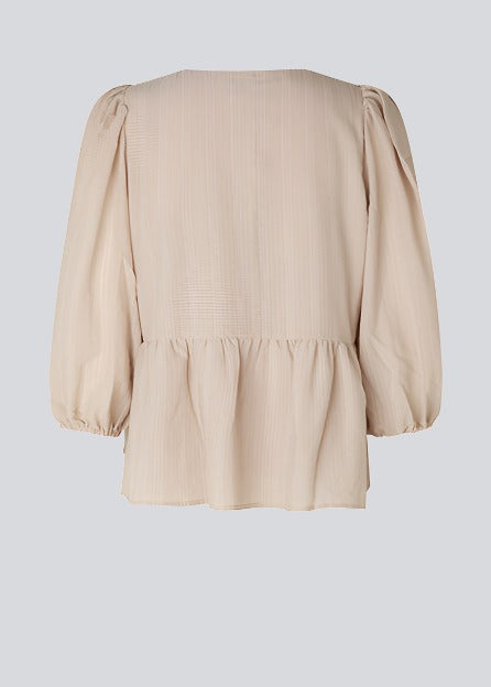 Top i beige i løs silhuet med 3/4 lange pufærmer, v-udskæring i halsen og en skæring i taljen, der giver ekstra volumen på den nederste del af toppen.