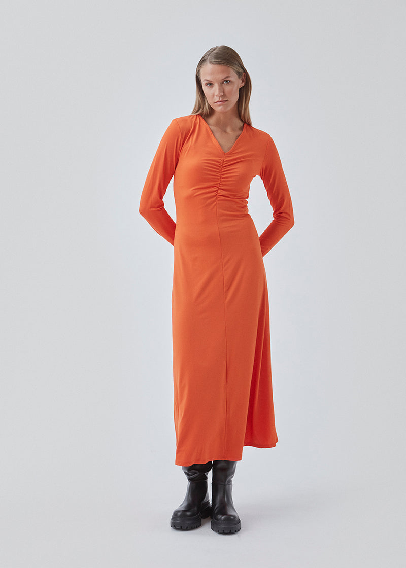 Tætsiddende kjole i orange i strækbar kvalitet med A-facon. BartoMD dress har lange ærmer og v-udskæring i halsen med rynkedetalje ved taljen.