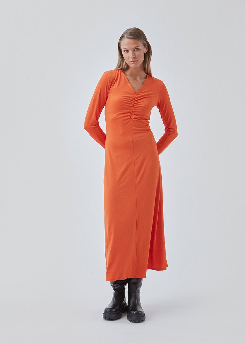 Tætsiddende kjole i orange i strækbar kvalitet med A-facon. BartoMD dress har lange ærmer og v-udskæring i halsen med rynkedetalje ved taljen.