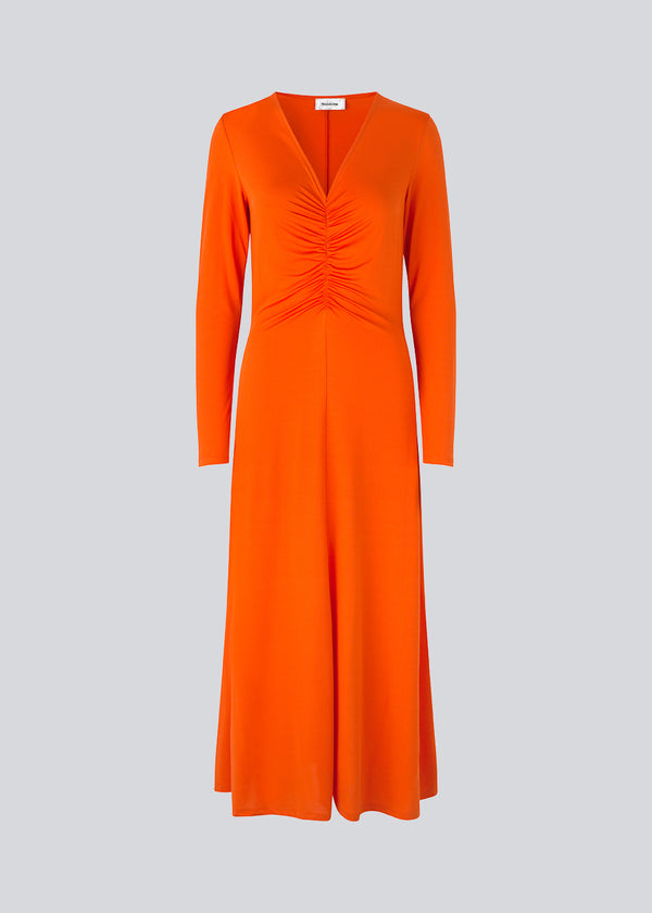 Tætsiddende kjole i orange i strækbar kvalitet med A-facon. BartoMD dress har lange ærmer og v-udskæring i halsen med rynkedetalje ved taljen.