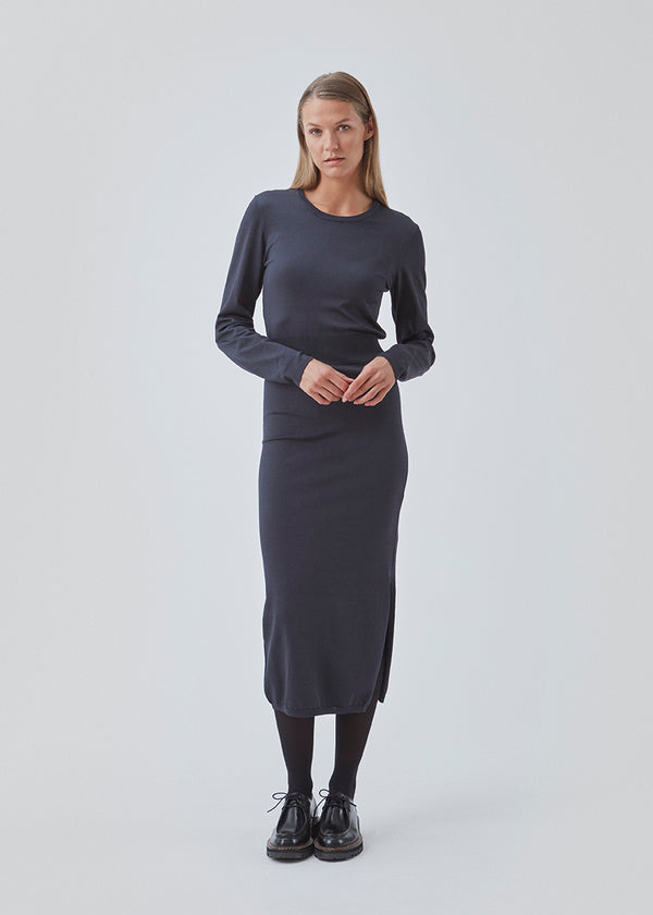 Midi-kjole i mørkeblå i strikket kvalitet med tætsiddende pasform. BilgeMD dress har en rund hals, lange ærmer, ribstrikket detalje ved taljen samt slids i den ene side.