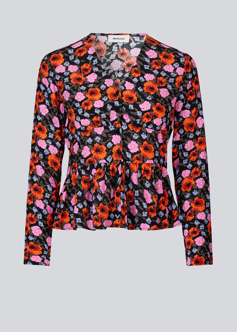BonMD print top har v-udskæring med knaplukning fortil og skæring i taljen med peplum. Lange, smalle ærmer.