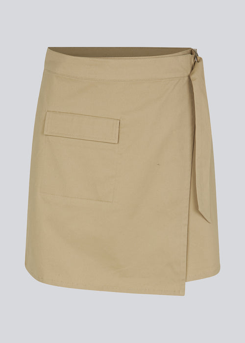 Kort nederdel med cargo-detaljer i vævet bomuldstwill. CalaMD skirt har wrap detalje med D-ring, asymmetriske detaljer og påsat lomme foran. Modellen er 177 cm og har en størrelse S/36 på.  Shop matchende jakke: CalaMD jacket