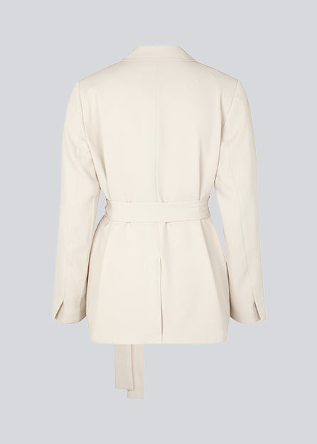 CayaMD blazer i beige har en afslappet pasform med klassiske detaljer med et twist med bindebælte i taljen. Fremstillet af genanvendte materialer. Modellen er 177 cm og har en størrelse S/36 på.  Style med de matchende bukser: CayaMD pants.