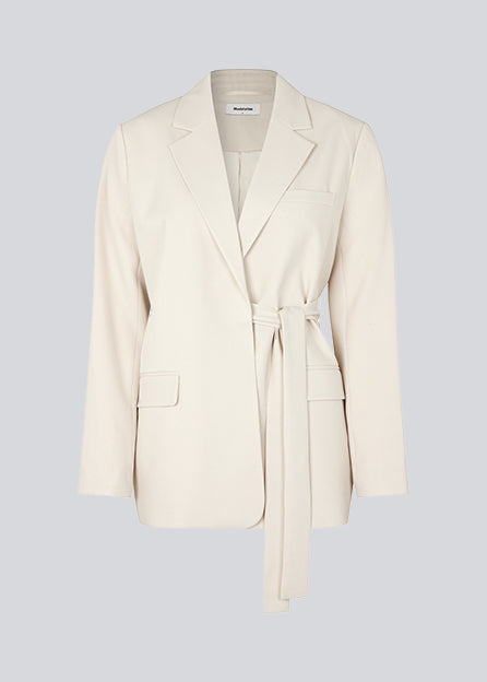 CayaMD blazer i beige har en afslappet pasform med klassiske detaljer med et twist med bindebælte i taljen. Fremstillet af genanvendte materialer. Modellen er 177 cm og har en størrelse S/36 på.  Style med de matchende bukser: CayaMD pants.