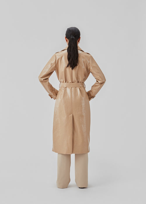 Frakke i skinnende materiale. CollinsMD coat har et klassisk trenchcoat-look med bred reverskrave, knaplukning og bindebælte i taljen.