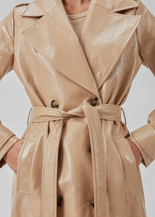 Frakke i skinnende materiale. CollinsMD coat har et klassisk trenchcoat-look med bred reverskrave, knaplukning og bindebælte i taljen.