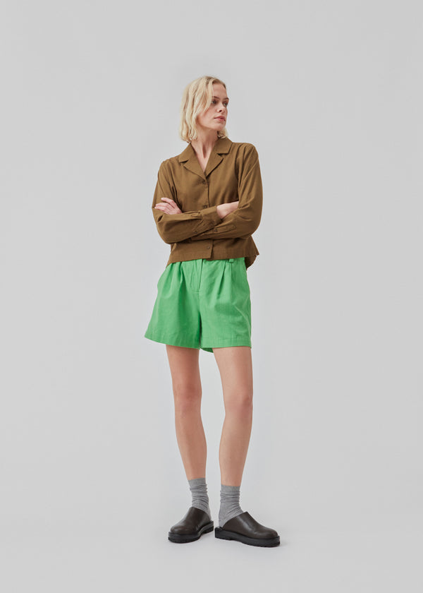 Bomuldsshorts i grøn med brede ben. CydneyMD shorts har et skræddersyet udtryk med plisseringer foran og paspolerede lommer bagpå. Modellen er 174 cm og har en størrelse S/36 på.