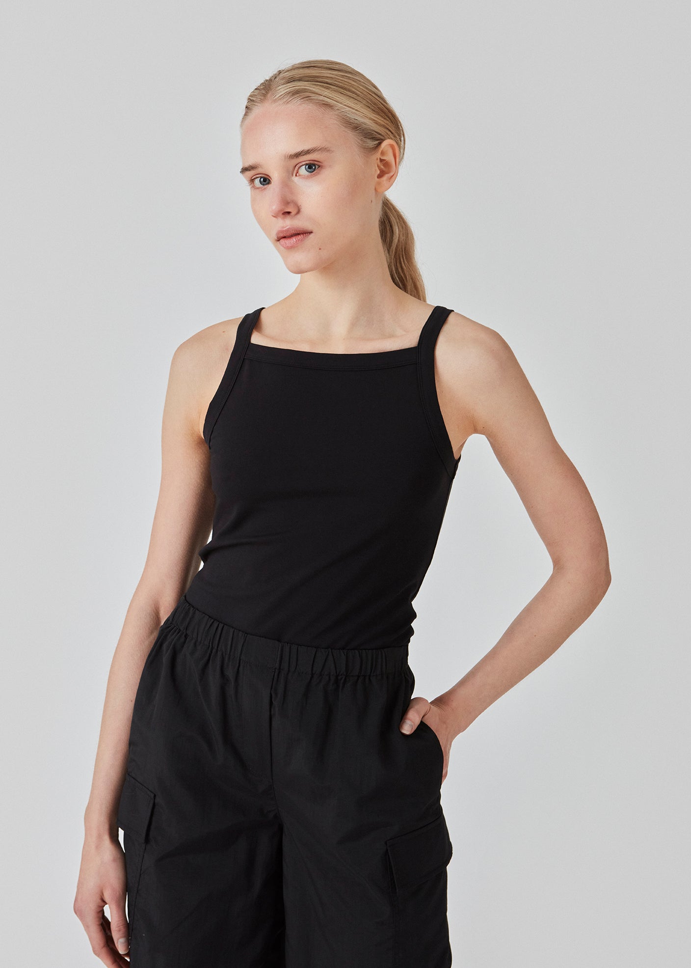 Tætsiddende basic sort top med høj og lige udskæring i halsen. DaeMD top er fremstillet i en ribstrikket økologisk bomuld. Modellen er 177 cm og har en størrelse S/36 på.