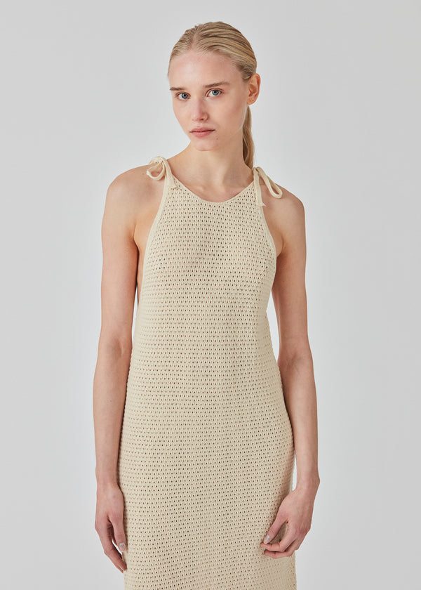 Hulstrikket kjole i beige i økologisk bomuld. DariaMD dress har et slim fit med langt skørt og stropper der bindes over skulderen. Modellen er 177 cm og har en størrelse S/36 på.