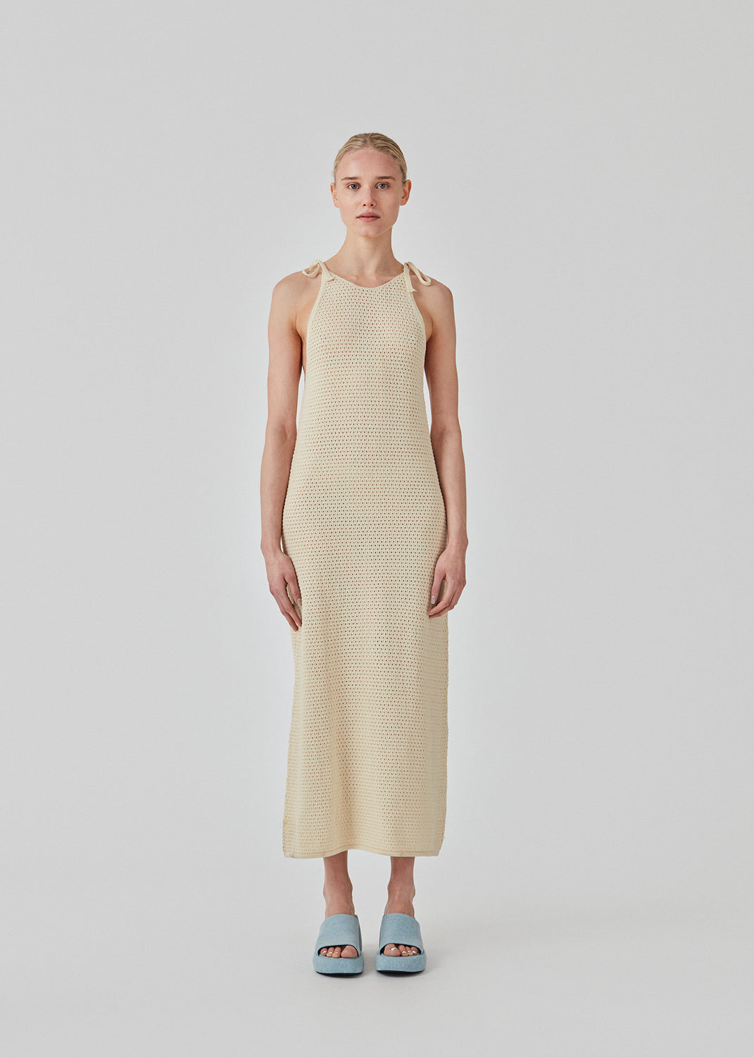 Hulstrikket kjole i beige i økologisk bomuld. DariaMD dress har et slim fit med langt skørt og stropper der bindes over skulderen. Modellen er 177 cm og har en størrelse S/36 på.