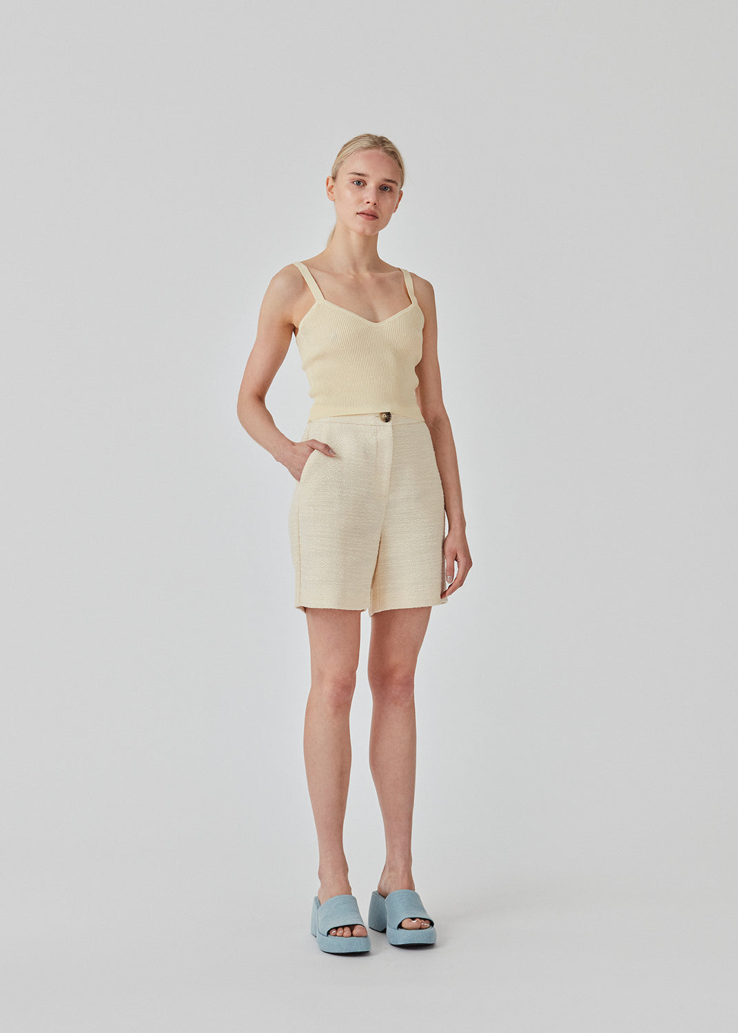 Råhvid crop top i ribstrikket kvalitet. DorisMD top har smalle stropper, v-udskæring oget tætsiddende fit. Modellen er 177 cm og har en størrelse S/36 på.