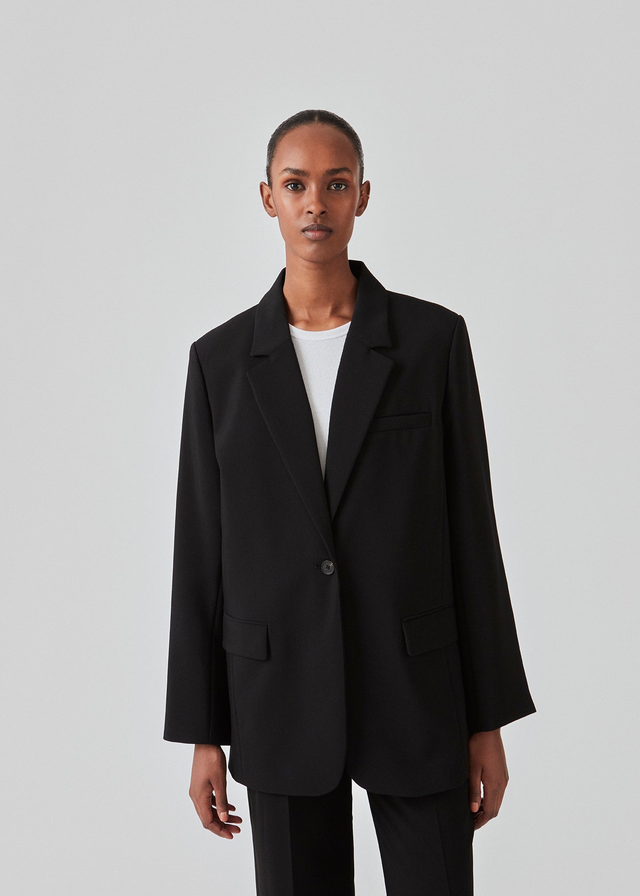 Gale blazer i sort har et klassisk og elegant design, som kommer til udtryk i den flotte reverskrave og den lange pasform. Blazeren har knaplukning fortil og en brystlomme i venstre side. Style blazeren med matchende bukser: Gale pants i sort, GaleMD shorts, eller: Gale straight pants.   Modellen er 177 cm og har en størrelse S/36 på.  Blazeren er stor i størrelsen. Vi anbefaler at gå en størrelse ned.