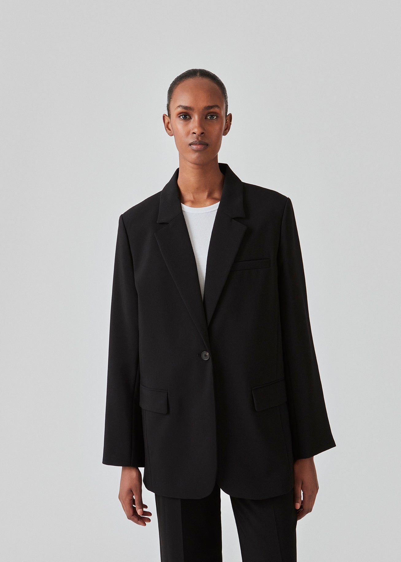 Gale blazer i sort har et klassisk og elegant design, som kommer til udtryk i den flotte reverskrave og den lange pasform. Blazeren har knaplukning fortil og en brystlomme i venstre side. Style blazeren med matchende bukser: Gale pants i sort, GaleMD shorts, eller: Gale straight pants.   Modellen er 177 cm og har en størrelse S/36 på.  Blazeren er stor i størrelsen. Vi anbefaler at gå en størrelse ned.