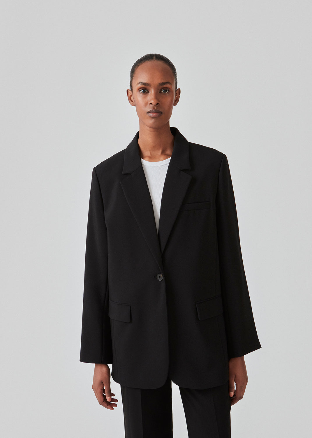 Gale blazer i sort har et klassisk og elegant design, som kommer til udtryk i den flotte reverskrave og den lange pasform. Blazeren har knaplukning fortil og en brystlomme i venstre side. Style blazeren med matchende bukser: Gale pants i sort, GaleMD shorts, eller: Gale straight pants.   Modellen er 177 cm og har en størrelse S/36 på.  Blazeren er stor i størrelsen. Vi anbefaler at gå en størrelse ned.