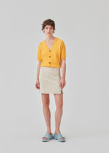 Trendy cardigan i gul med korte pufærmer og knaplukning fortil. Irene cardigan er lavet i et blødt materiale, perfekt til de tidlige forårsdage. Modellen er 174 cm og har en størrelse S/36 på