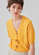 Trendy cardigan i gul med korte pufærmer og knaplukning fortil. Irene cardigan er lavet i et blødt materiale, perfekt til de tidlige forårsdage. Modellen er 174 cm og har en størrelse S/36 på