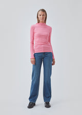 Tætsiddende trøje i pink med mellem høj krave. Issy t-neck har feminine flæsekanter ved hals og ærmer. Kvaliteten er en blød jersey med et feminint pointelle mønster.