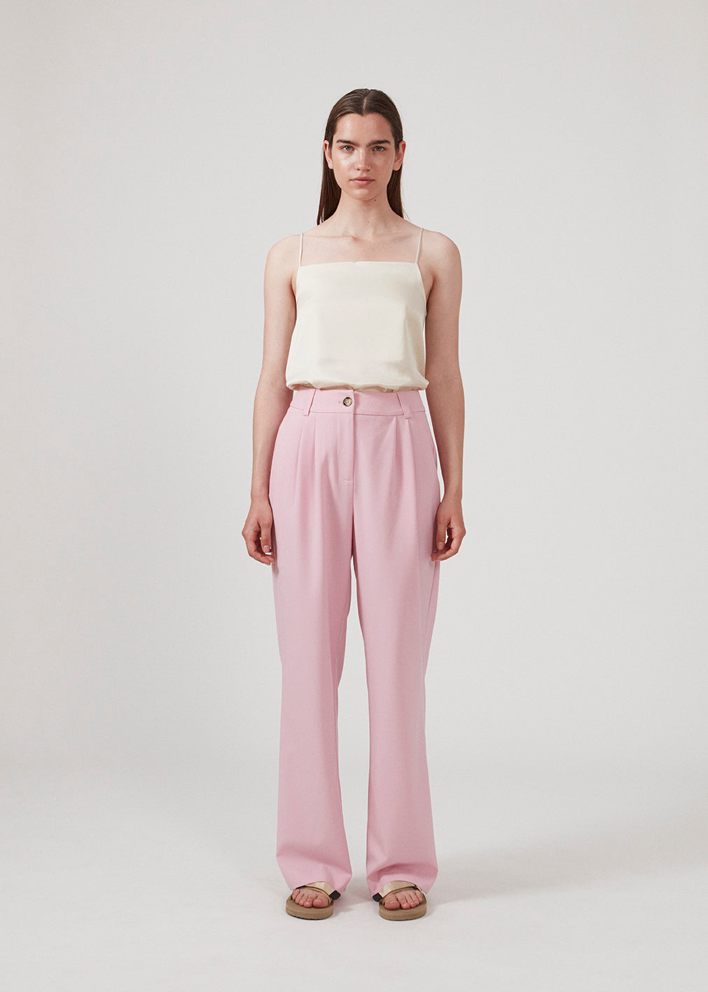 Satin top i beige med justerbare spaghetti-stropper og enkelt udtryk. CarwynMD top har A-facon og lige udskæring. Modellen er 177 cm og har en størrelse S/36 på.