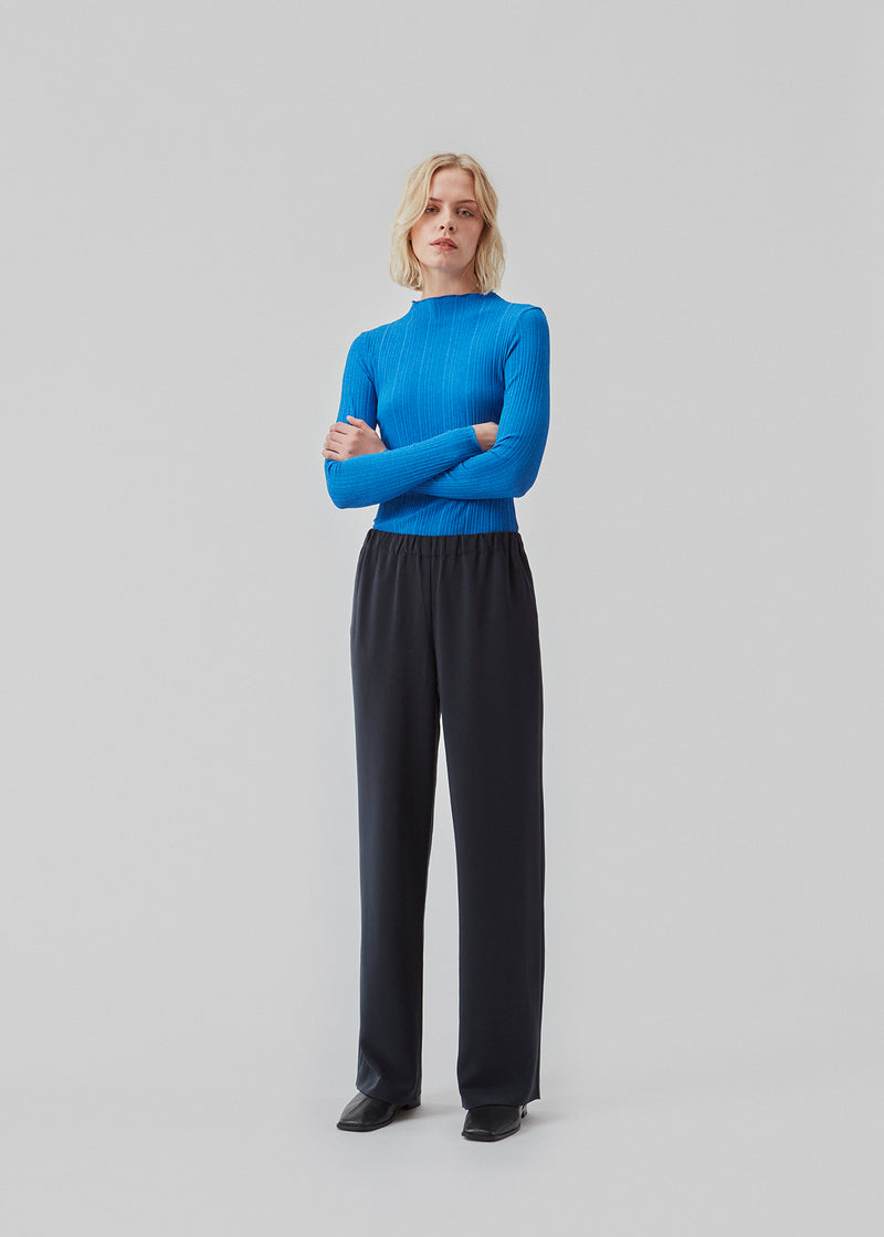 Tætsiddende, langærmet blå t-shirt med flæset kant på ærmer, ved halsen og bund.   Modellen er 177 cm og har en størrelse S/36 på.