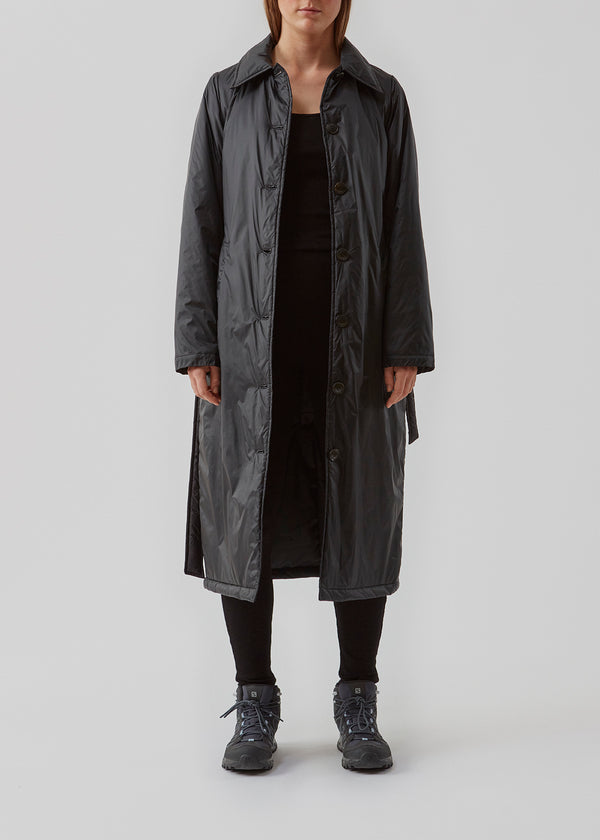 Sporty frakke med krave, knapper og taljebælte. Oma jacket er en cool nylonfrakke i en rummelig men feminin pasform. Frakkens lette fyld er 100% genanvendt polyester. Modellen er 173 cm og har en størrelse S/36 på