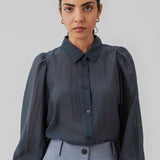Klassisk skjorte i mørkeblå i et let og luftigt materiale. Oskar shirt har en afslappet pasform med voluminøse ballonærmer der afsluttes med en bred manchet. Skjorten er en smule gennemsigtig som skaber et ultra feminint udtryk. Modellen er 174 cm og har en størrelse S/36 på.