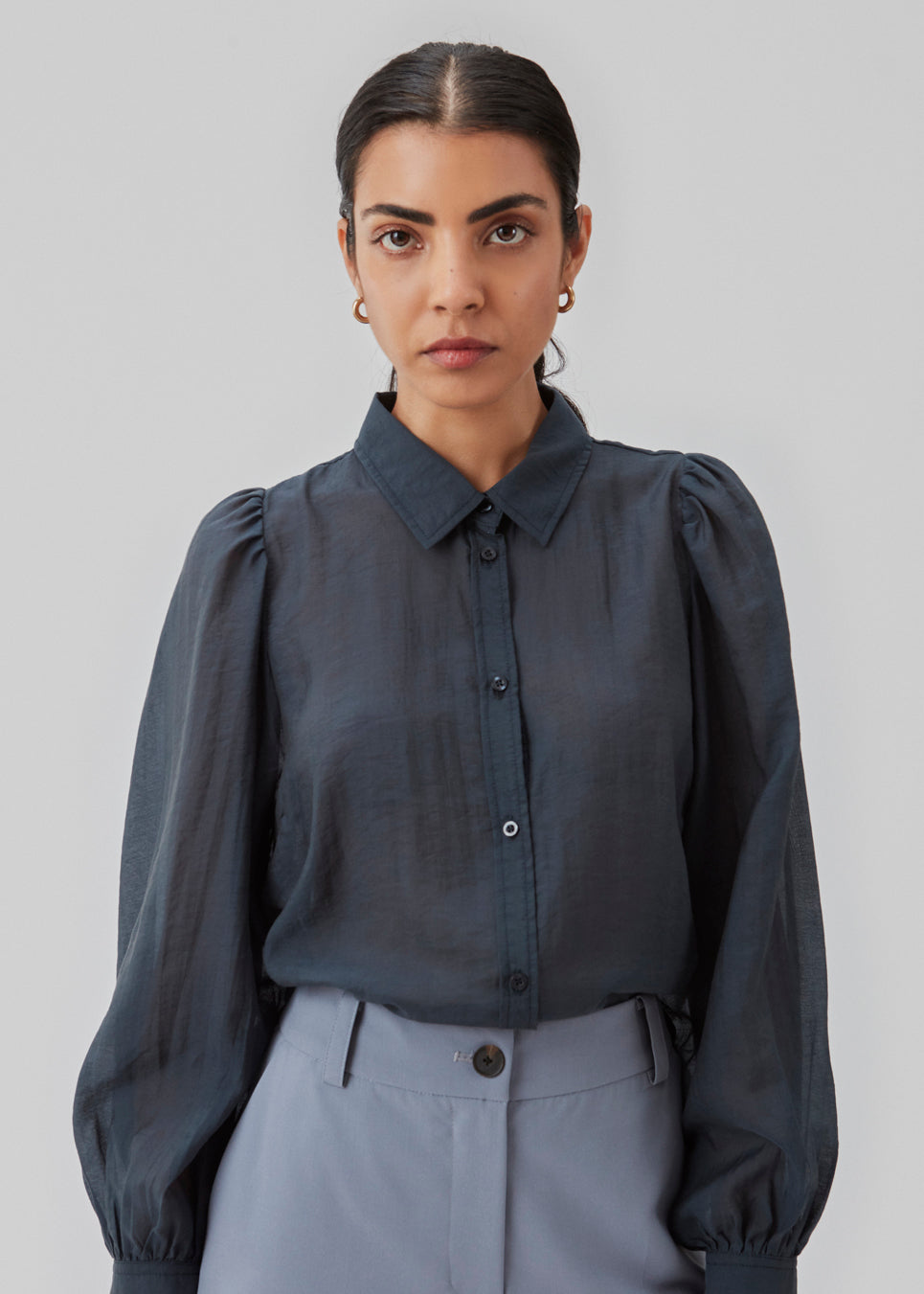 Klassisk skjorte i mørkeblå i et let og luftigt materiale. Oskar shirt har en afslappet pasform med voluminøse ballonærmer der afsluttes med en bred manchet. Skjorten er en smule gennemsigtig som skaber et ultra feminint udtryk. Modellen er 174 cm og har en størrelse S/36 på.