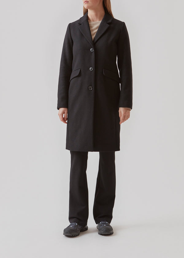 Smuk og klassisk knælang uldfrakke. Pamela coat i farven Black bliver knappet fortil af 3 store knapper og er taljeret, som giver et feminint udtryk. På grund af den høje kvalitet af uld, vil den være det oplagte valg at bruge til både efterår og de milde vintre.