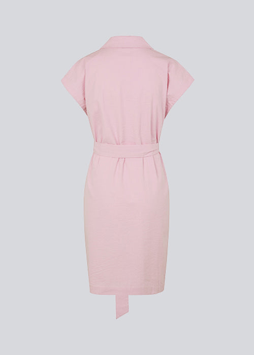 Panne dress er en bomuldskjole i lyserød med smuk silhouet. Kjolen har desuden en fin krave, bindebånd og et ærmeløst design med vide, firkantede skuldre. Modellen er 173 cm og har en størrelse S/36 på.