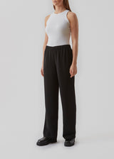 Bukser i mørkebrun i et simpelt design med brede ben. Perry pants har skrålommer i siden og en elastisk talje for et behageligt fit. Indersøm (S/36): 81 cm Bukserne forlænges med 0,5 cm for hver størrelse. Modellen har bukserne på i sort og er 173 cm og har en størrelse S/36 på