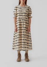 Midi kjole med korte pufærmer med elastik. Poem print dress har et batikfarvet print og er lavet i ansvarligt bomuld. Skørtet tilføjer masser af volumen og et feminint udtryk. Modellen er 173 cm og har en størrelse S/36 på