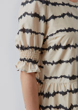 Midi kjole med korte pufærmer med elastik. Poem print dress har et batikfarvet print og er lavet i ansvarligt bomuld. Skørtet tilføjer masser af volumen og et feminint udtryk. Modellen er 173 cm og har en størrelse S/36 på
