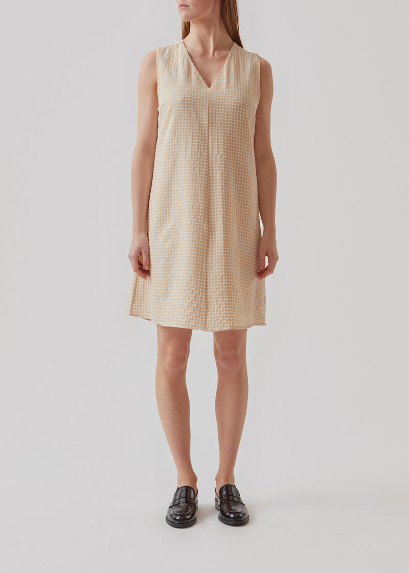 Ærmeløs kort kjole i beige i struktureret tern. RimmeMD dress er voluminøs i silhuetten og har en dyb v-formet halsudskæring foran. Modellen er 173 cm og har en størrelse S/36 på.¨