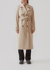 Klassisk, dobbeltradet uldfrakke i beige med krave og revers. ShayMD coat har bredt taljebælte, skulderstropper, brede manchetter og stormflap. Med for og slids bagpå.