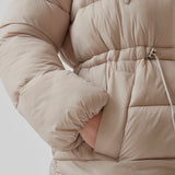 Polstret jakke i beige med oversize pasform and justerbar talje. StellaMD jacket har opretstående krave, hætte, tovejslynlås og to paspolerede forlommer.
