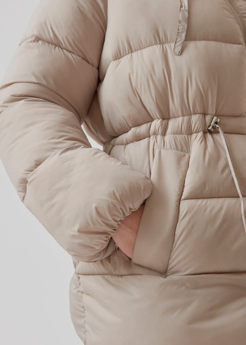 Polstret jakke i beige med oversize pasform and justerbar talje. StellaMD jacket har opretstående krave, hætte, tovejslynlås og to paspolerede forlommer.
