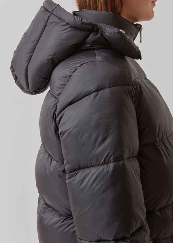 Knælang fakke i sort i vatteret nylon. StellaMD long jacket har en afslappet pasform med lange ærmer, hætte og opretstående krave. Tovejslynlås, justerbar hætte og diskrete sidelommer.