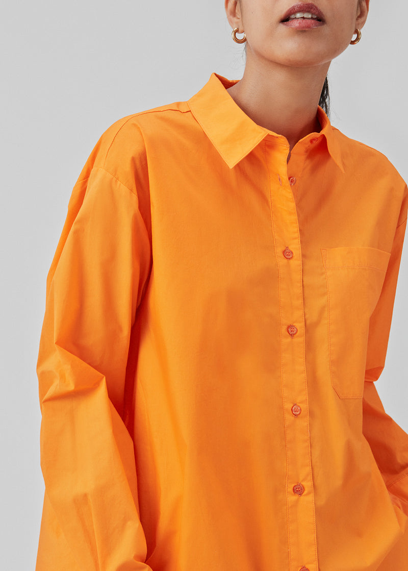 Luftig orange skjorte i økologisk bomuldspoplin i orange. TapirMD shirt har krave og knapper foran, samt åben brystlomme. Lav skuldersøm og lange ærmer med manchet og knap. Broderet logo foran.  Modellen er 177 cm og har en størrelse S/36 på.