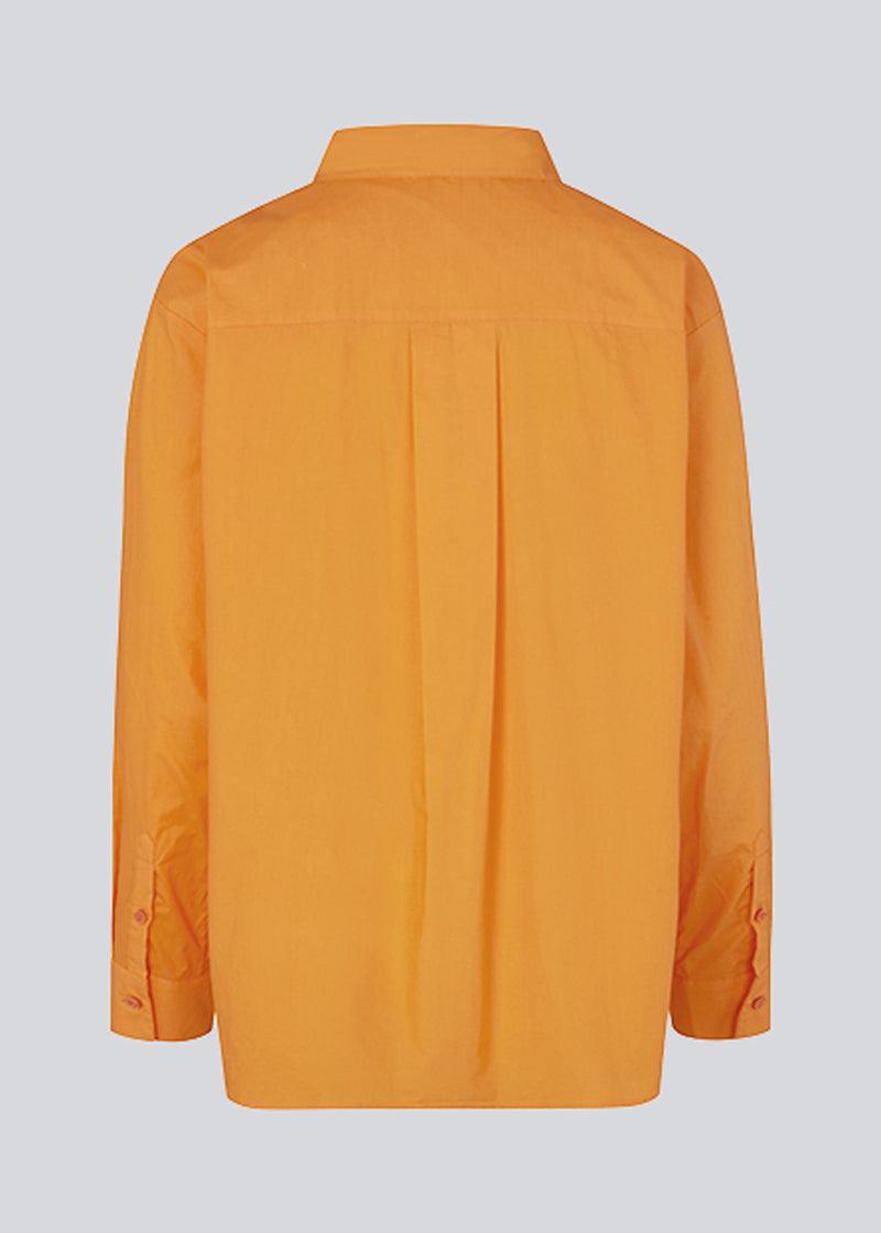 Luftig orange skjorte i økologisk bomuldspoplin i orange. TapirMD shirt har krave og knapper foran, samt åben brystlomme. Lav skuldersøm og lange ærmer med manchet og knap. Broderet logo foran.