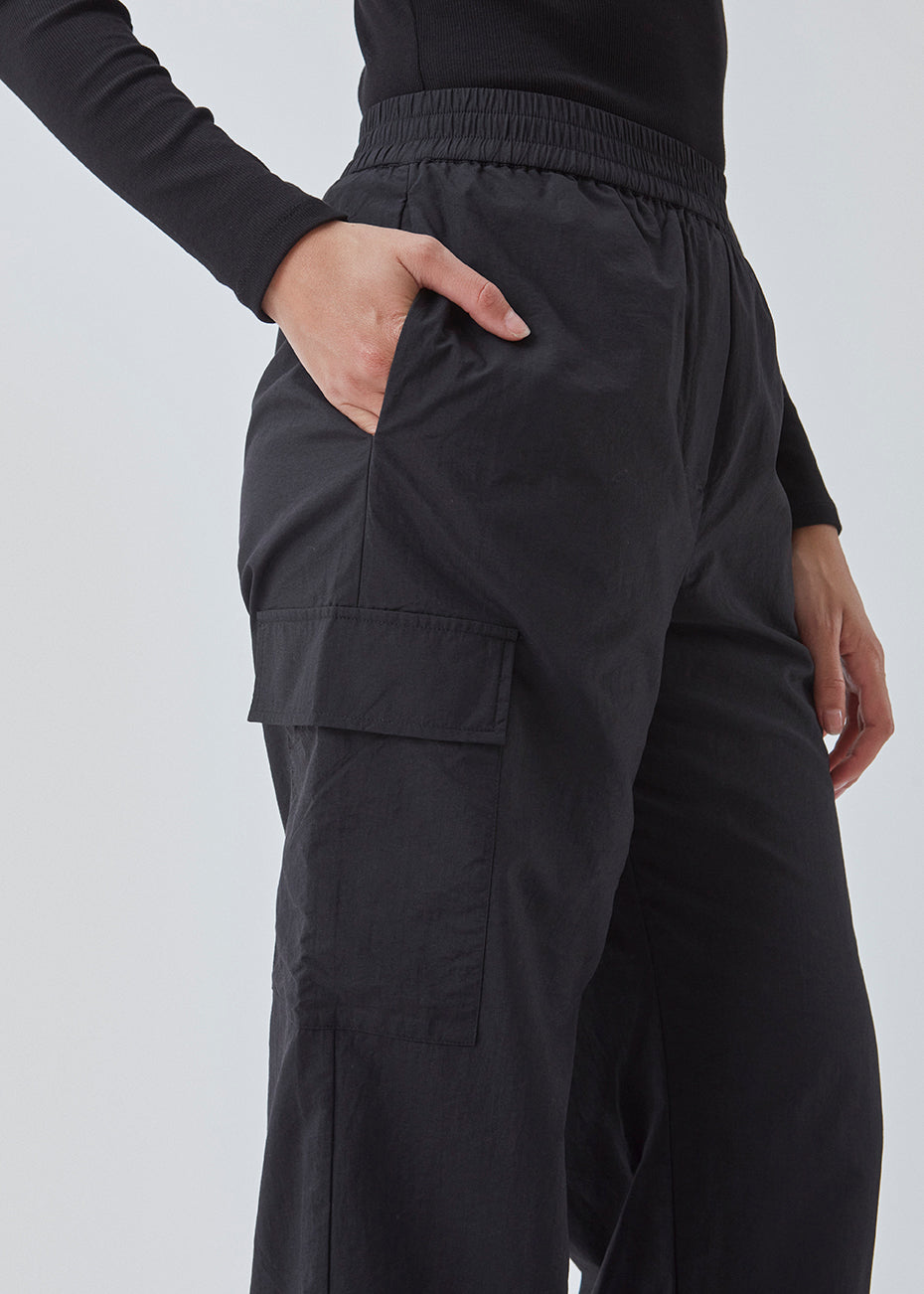 Cargobukser i nylon med elastisk talje og justerbare kanter med løbesnor. TrentMD pants har påsyede lommer på benene. Farven er sort.  TrentMD pants er lavet på samme model som vores meget populære og udsolgte AmayaMD pants. Dog i en kraftigere kvalitet, perfekt til efterår og vinter. 