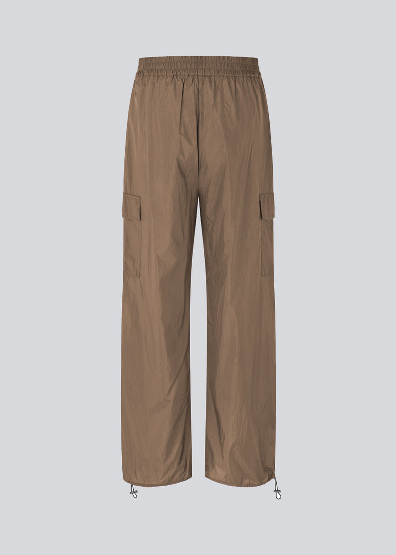 Bukser i genvundet nylon i farven Dune. AmayaMD pants har høj talje og lige ben med justerbar elastik forneden. Beklædt elastik i taljen og to store lommer på benene.