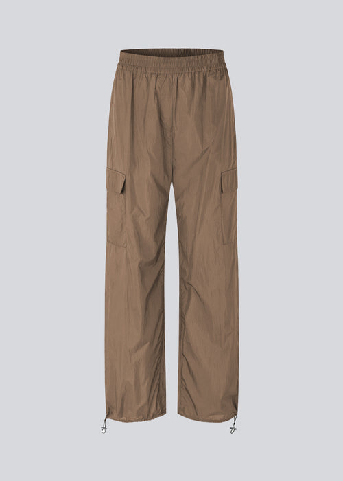 Bukser i genvundet nylon i farven Dune. AmayaMD pants har høj talje og lige ben med justerbar elastik forneden. Beklædt elastik i taljen og to store lommer på benene.